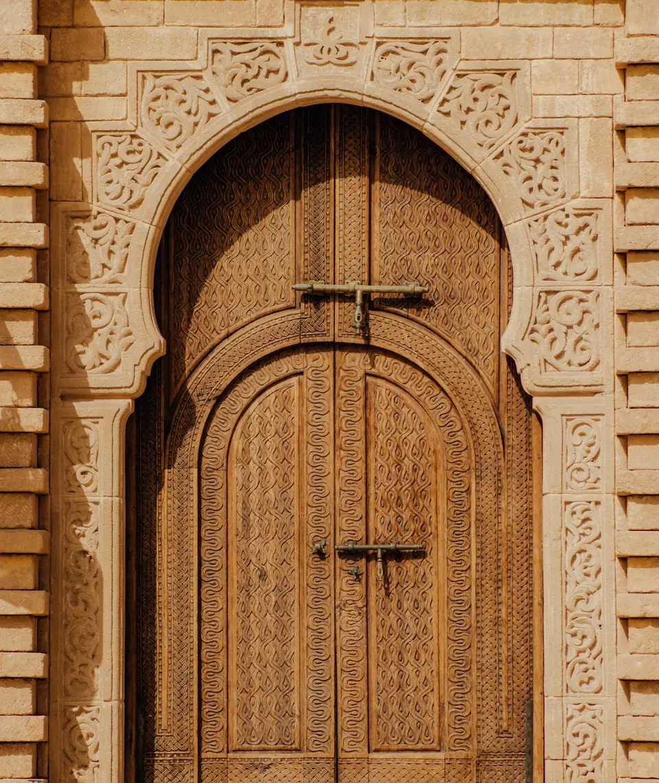 Porte en bois sculpté sous un arc outrepassé en plâtre ciselé