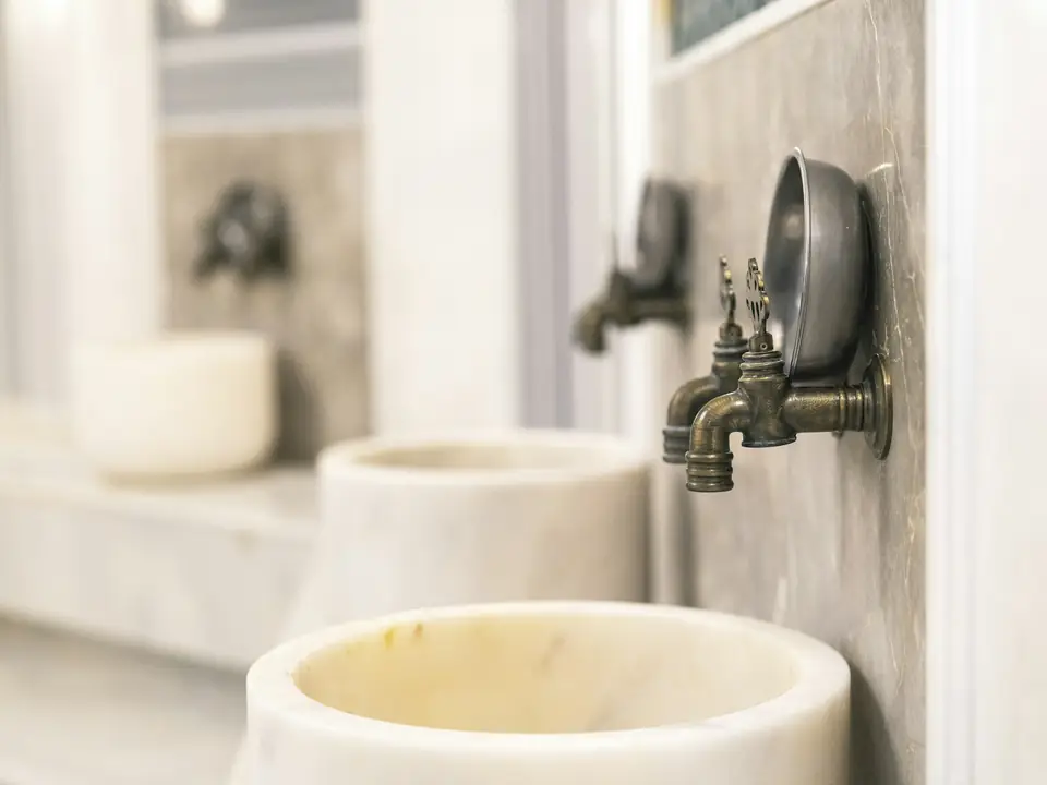 Vasques en pierre et robinets en laiton dans une salle d’eau traditionnelle